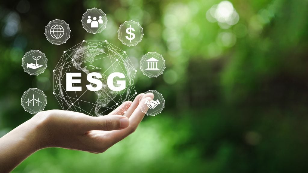 Concepto de icono ESG en la mano para el medio ambiente, la sociedad y la gobernanza en negocios sostenibles y éticos en la conexión de red sobre un fondo verde.