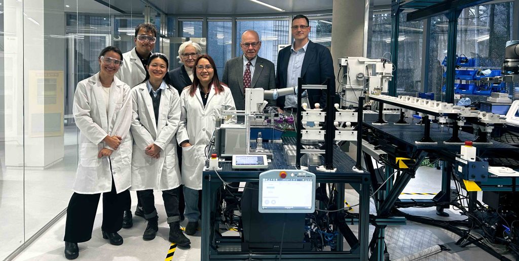 Professionals in lab coats and business attire stand in a modern British Columbia, Canada lab featuring advanced scientific equipment and technology.