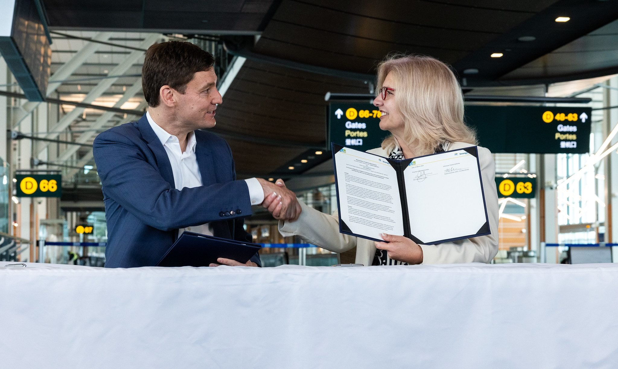 Premier David Eby and YVR CEO Tamara Vrooman shake hands.