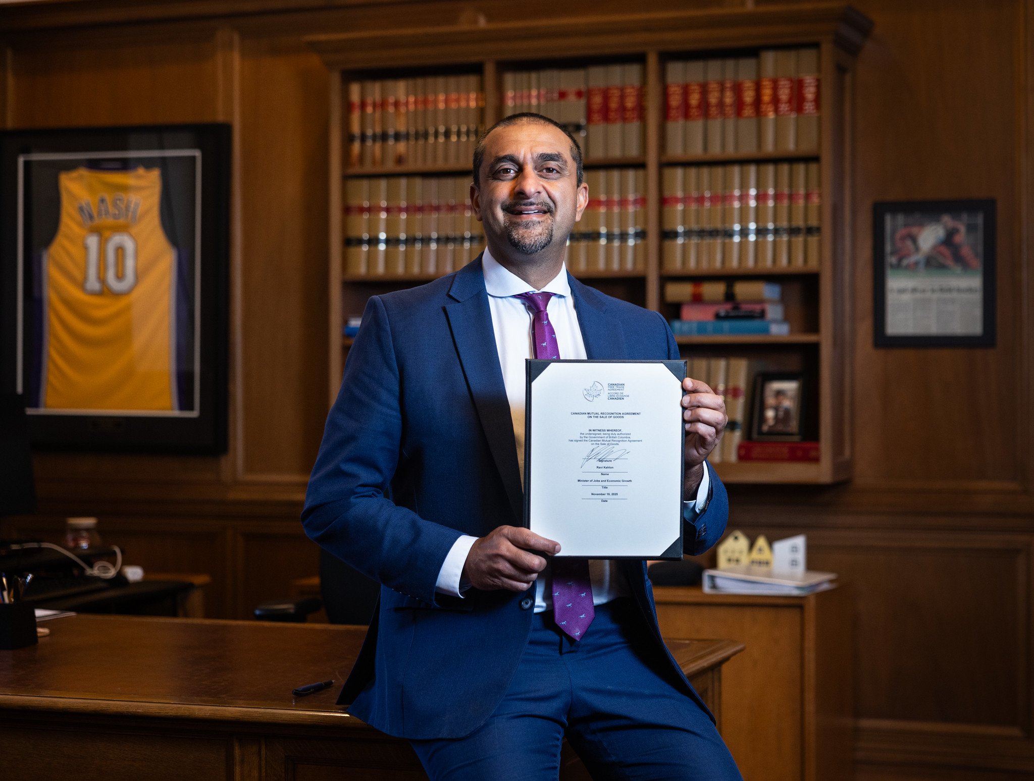 The Honourable Ravi Kahlon, Minister of Jobs and Economic Growth, holds the signed agreement in his office.