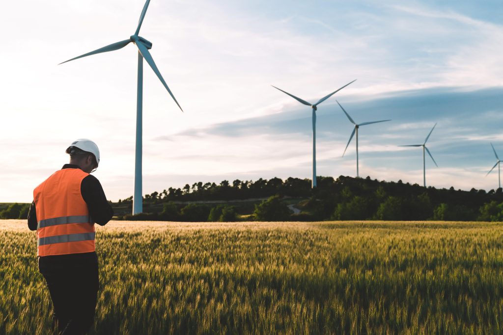 Worker standing under wind turbine