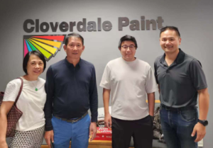 Group photo of four people standing in front of the Cloverdale Paint sign 