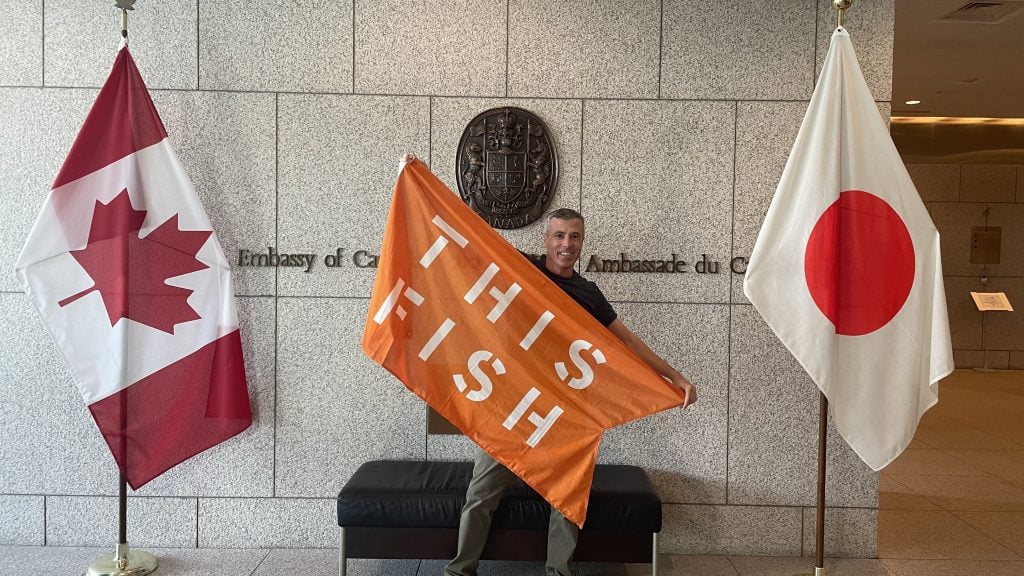 ThisFish CEO poses with ThisFish flag at the Canadian Embassy in Japan.