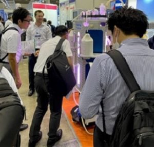 Several people crowded over Industrial Plankton's photobioreactors.