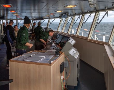 Workers inside a ship in front of a navigation system