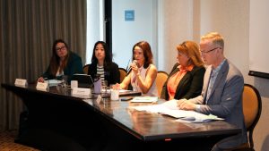 Five people sitting behind a desk speaking to attendees.