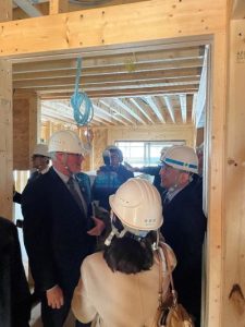 People wearing hard hats inside a building being built with wood. 