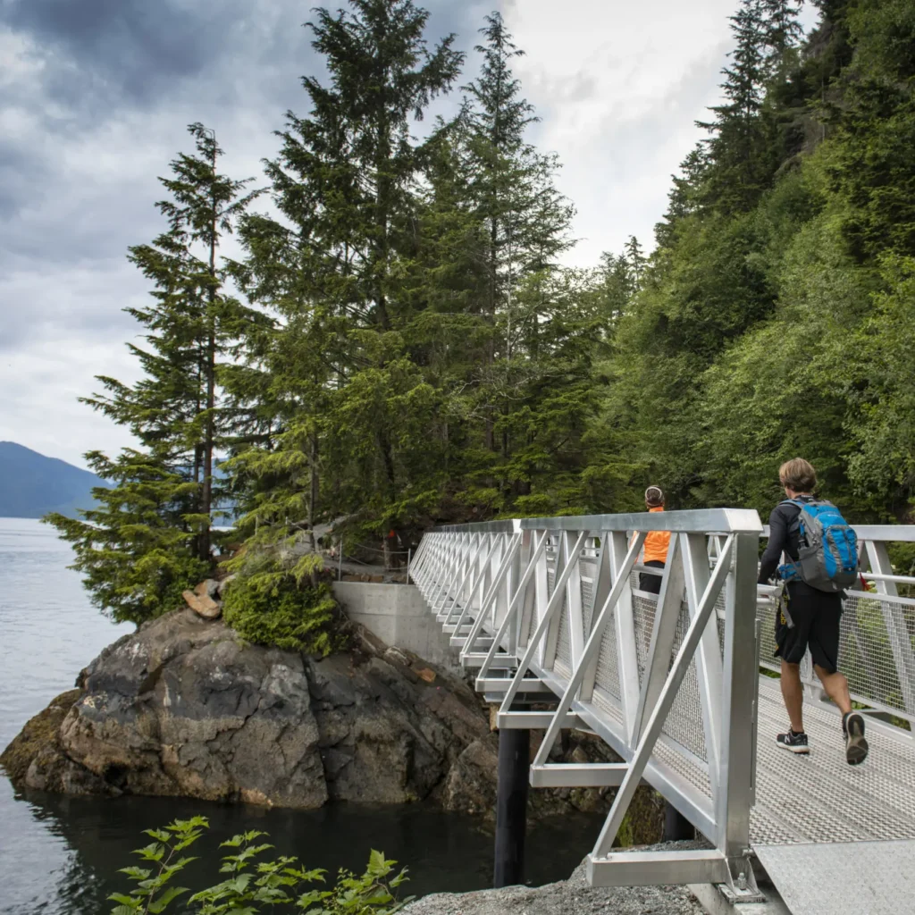 Des gens traversent un pont lors d’une randonnée le long de la côte à Prince Rupert.