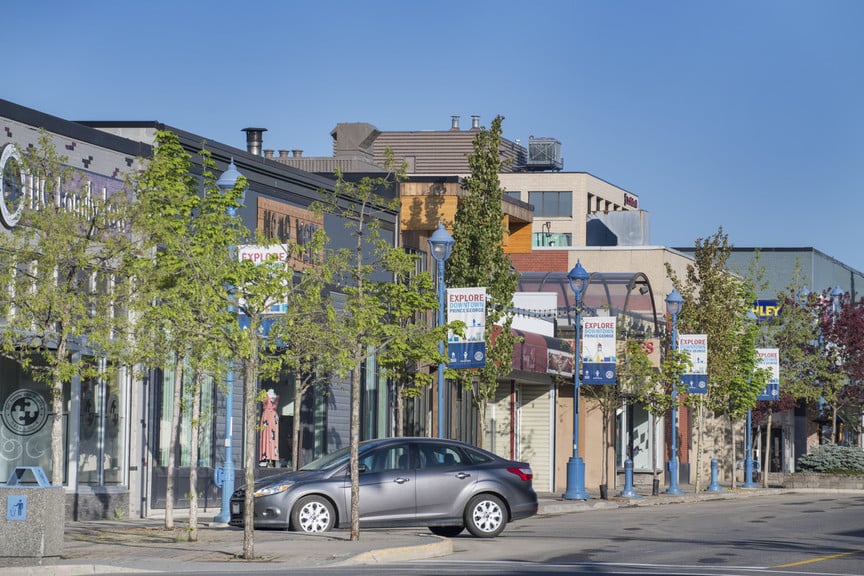 Downtown Prince George, with businesses and car parked on the road.