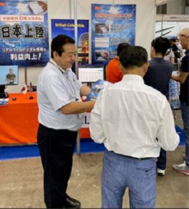 Trade show posters in the background people speaking in the foreground. 