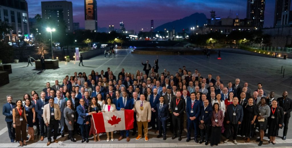 Group of people at dusk with Canadian flag, cityscape and mountains in background, highlighting British Columbia’s vibrant economy and natural assets.
