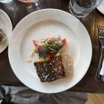 A serving of seared fish topped with herbs and a vegetable medley, showcasing British Columbia, Canada’s agri-food and seafood production on a white plate.