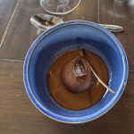 A blue bowl of chocolate mousse with chocolate garnish on a wooden table with a spoon, showcasing British Columbia’s value-added food sector.