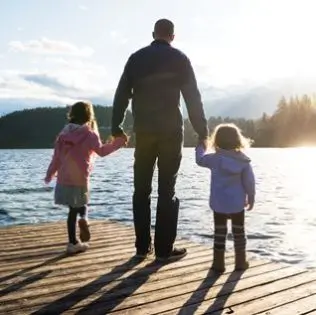 Father holding his two daughters hands.