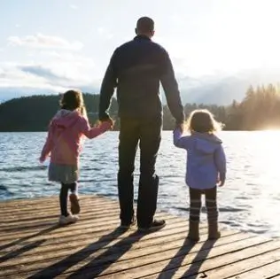 Padre sosteniendo las manos de sus dos hijas.